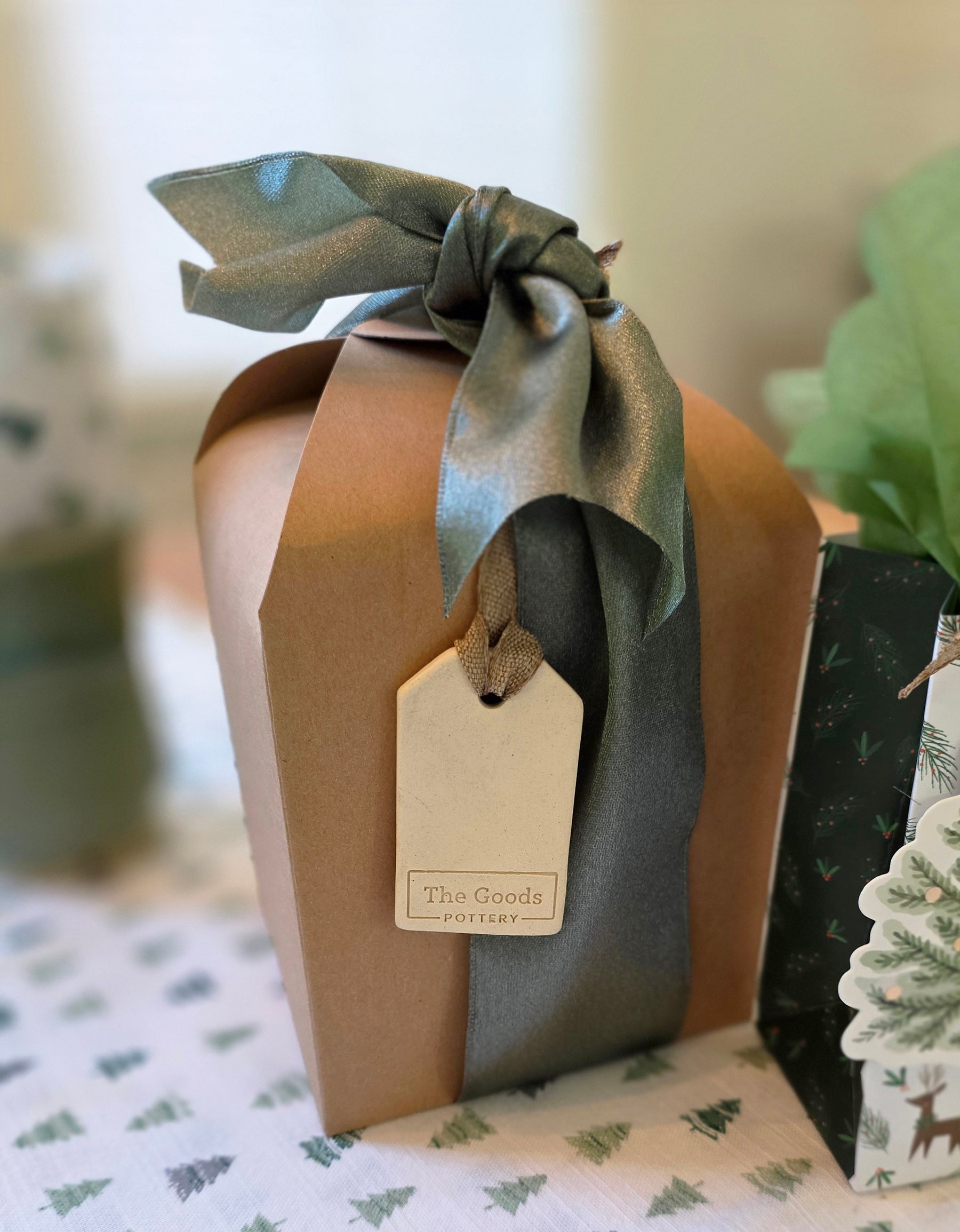 Gift box wrapped in brown paper with a green ribbon and tag on a patterned surface.